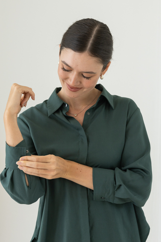 A woman wearing the Olive Basics Delilah All-Occasion TENCEL™ Shirt smiles and adjusts her cuff, highlighting the shirt’s comfort and effortless style.