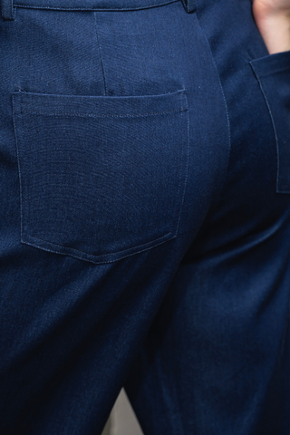 Close-up of the back of a person wearing Olive Basics Jesse Wide-leg Pocket Pants in dark blue Denim TENCEL, showcasing two rear pockets and part of their hand.