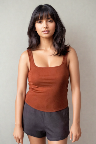 A woman with medium-length dark hair models the Olive Basics Esther Easy Latch Tank, featuring a reversible neckline and built-in bra padding, paired with black shorts against a plain light background.