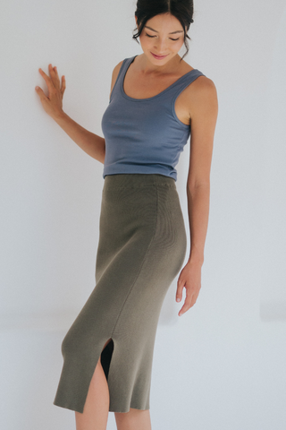 A woman wears the Olive Basics Esther Easy Latch Tank with built-in bra padding in blue and an olive green midi skirt with a front slit, standing against a white background.