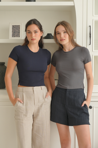Two women wearing navy and charcoal gray Diana Padded Tees with built-in bras, paired with light-colored trousers and dark shorts.