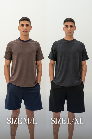 A man stands wearing a brown t-shirt and navy activewear shorts labeled SIZE M/L on the left, and a dark grey t-shirt with Olive Basics Noah Multi-Pocket Stretch Shorts in black labeled SIZE L/XL on the right.