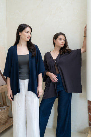 Two women stand indoors against a light wall, both wearing Olive Basics' Deborah Nursing Kimono Cardigans with wide sleeves; one pairs it with white pants, the other with dark blue pants, and both wear dark tops.