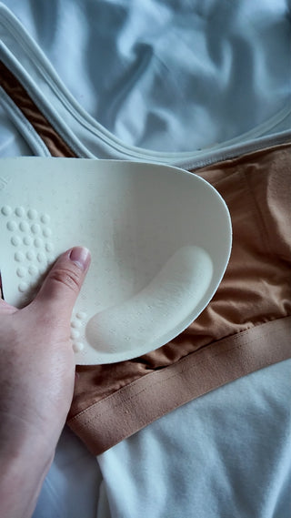 A hand lifting the removable contoured pad out of the Esther tank's built-in shelf band.