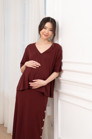 asian model with a baby bump leaning on a white wall, wearing tabitha tee & skirt co-ord set